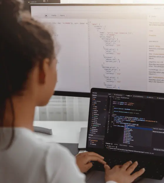 Person coding Cms Development Project on a laptop with large monitor display